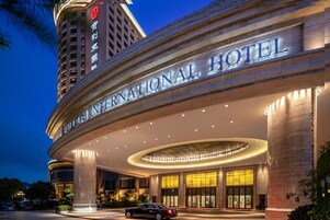 The exterior of the INTERNATIONAL HOTEL with a prominent entrance, large columns, and a well-lit facade.