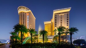 Een hotel met meerdere hoge gebouwen, palmbomen op de voorgrond en verlichte borden.