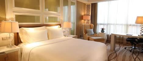 A hotel room with a large bed, two bedside tables with lamps, a desk with a chair, and a decorative wall panel.