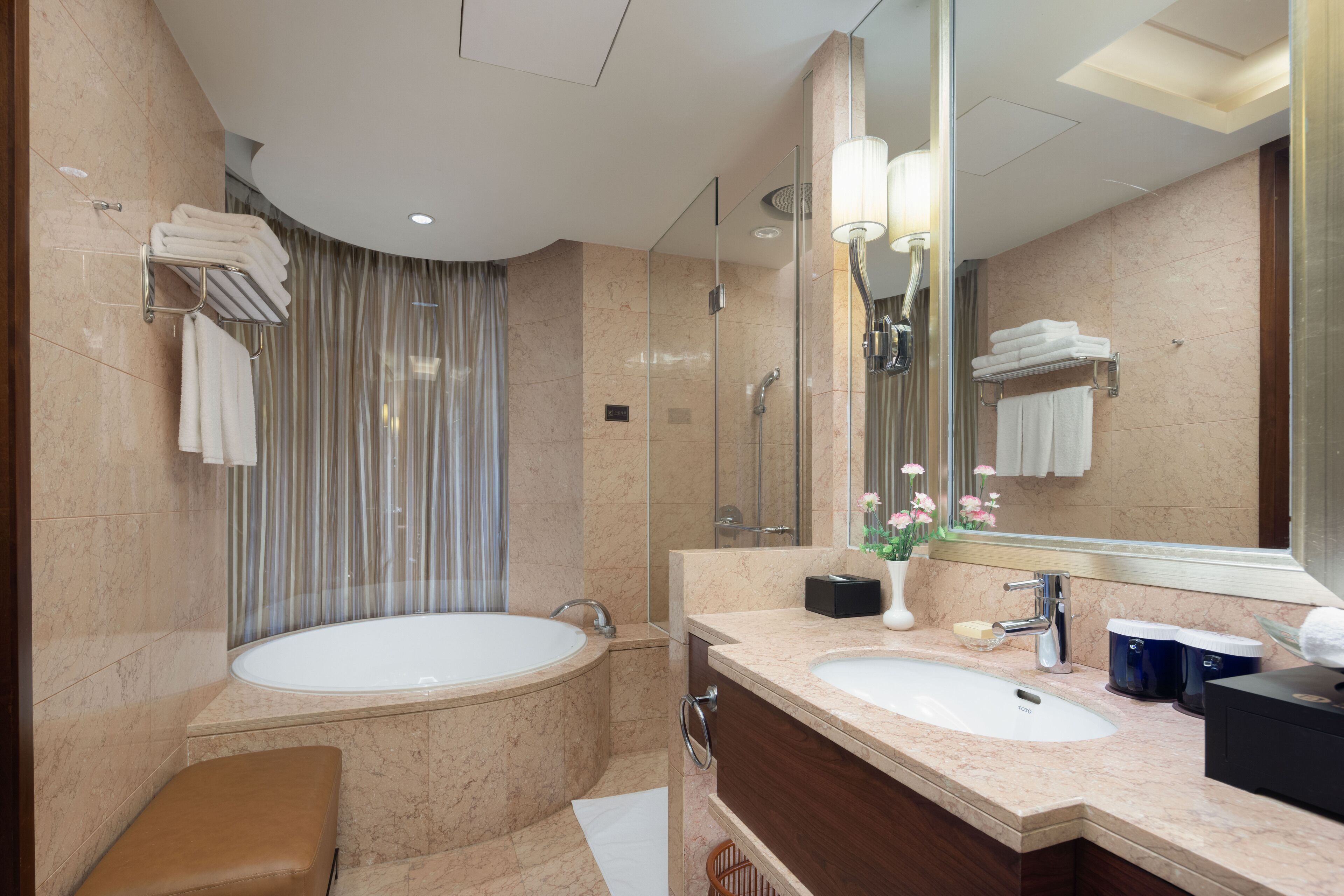 A modern bathroom with a large bathtub, a separate shower area, a vanity with a sink, and a large mirror.