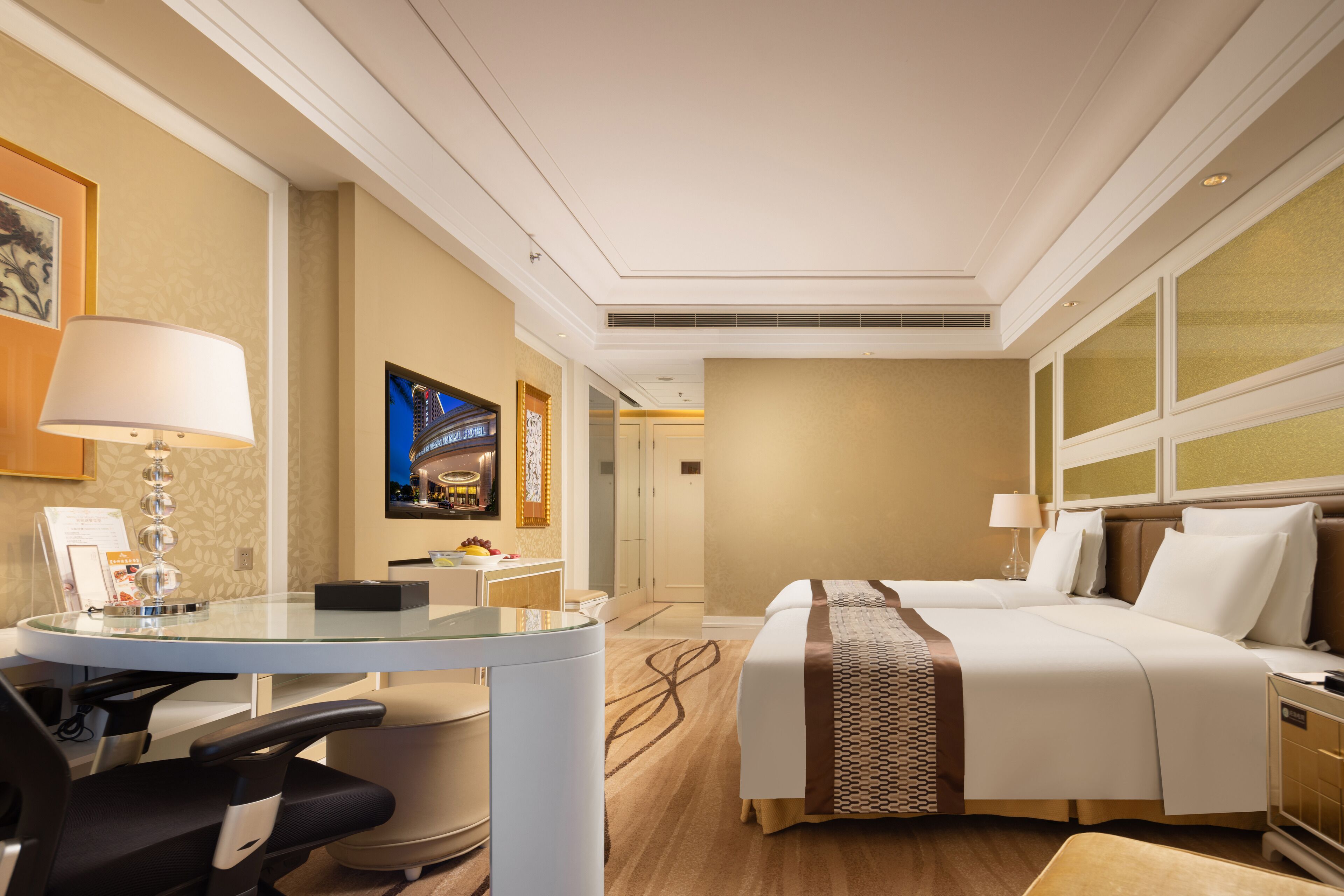 A hotel room with a bed, desk, chair, and a television.