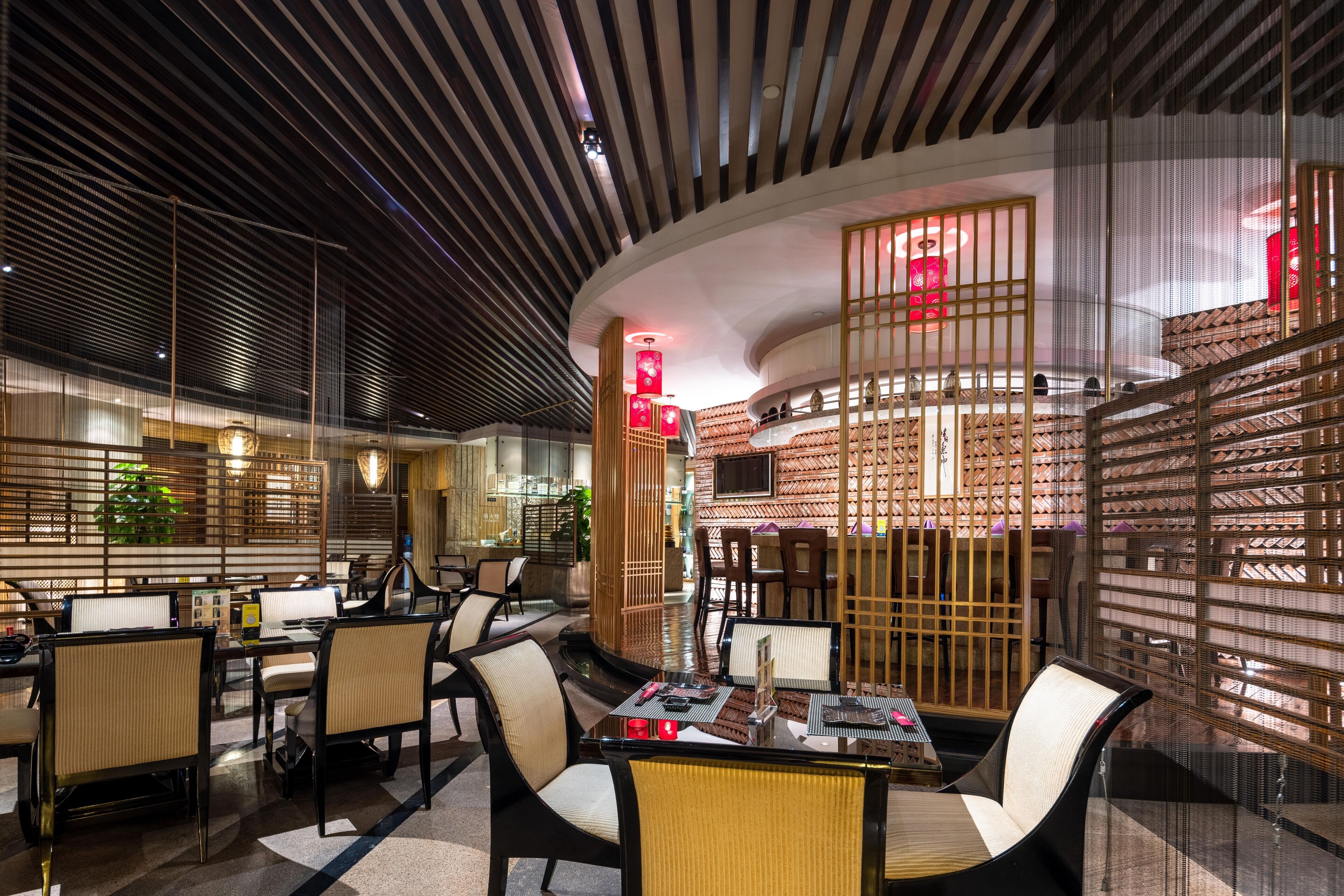 A modern restaurant with a curved ceiling, wooden partitions, and a variety of seating arrangements including tables and chairs.
