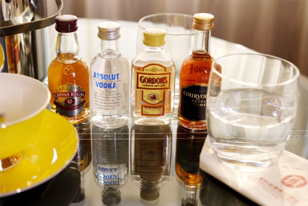 Uma mesa com várias garrafas de bebidas alcoólicas e um copo.
