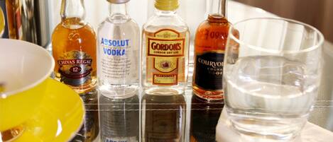 Uma mesa com várias garrafas de bebidas alcoólicas e um copo.