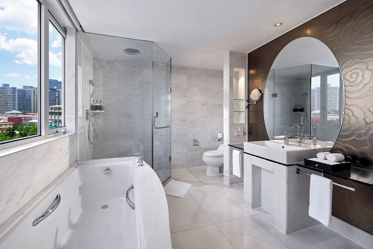 A modern bathroom with a large bathtub, a glass-enclosed shower, a toilet, and a vanity with a mirror.