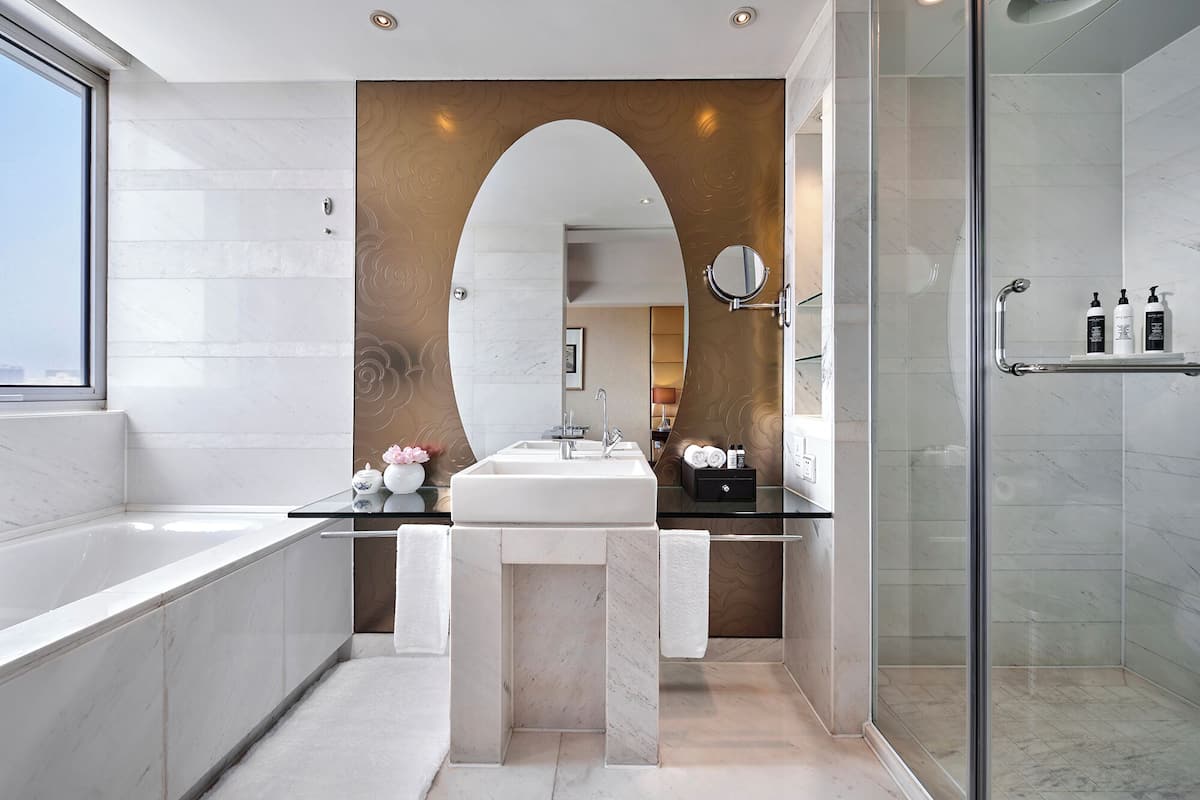 A modern bathroom with a glass shower enclosure, a freestanding bathtub, and a vanity with a large mirror.