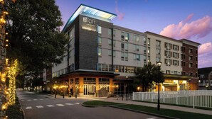 A modern hotel with a flat roof, multiple floors, and a well-lit entrance.