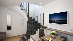Un intérieur moderne avec un escalier, un coin repas comprenant une table, des chaises et une plante en pot.