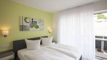 A hotel room with a bed, two bedside tables, a wall-mounted artwork, and a window with sheer curtains.