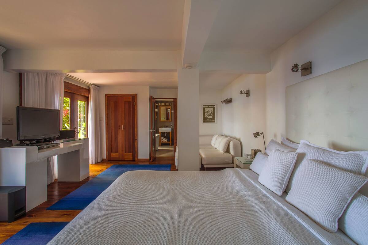 Une chambre d’hôtel avec un grand lit, un téléviseur posé sur un bureau et une salle de bain visible à travers une porte ouverte.