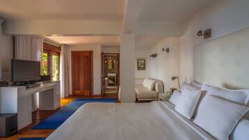 Una habitación de hotel con una cama grande, un televisor sobre un escritorio y un baño visible a través de una puerta abierta.