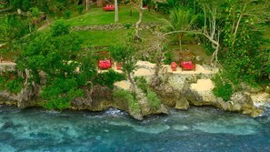 A coastal resort with multiple red cabanas on a rocky outcrop, overlooking clear blue waters. - Geejam (Port Antonio)
