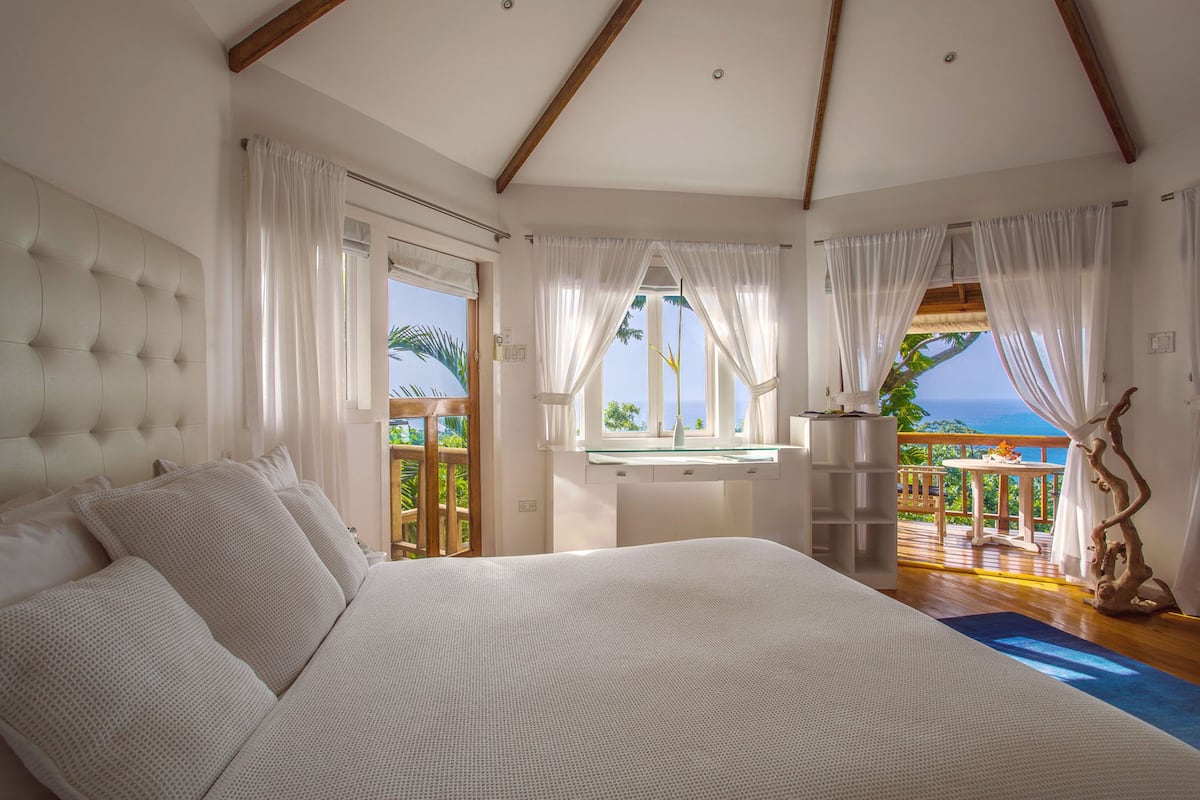 Une chambre spacieuse avec un grand lit, un bureau et une vue sur l’océan.