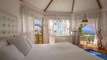 Um quarto espaçoso com uma cama grande, uma escrivaninha e vista para o oceano.
