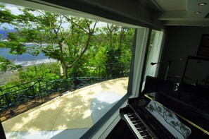 A piano near a large window overlooking a scenic view of trees and a body of water.