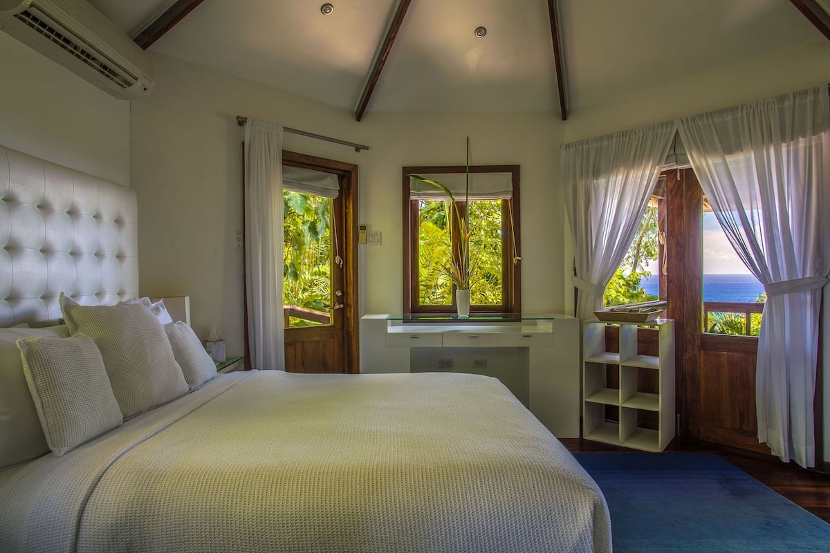 Une chambre avec un grand lit, une coiffeuse avec un miroir et une vue sur l’extérieur.