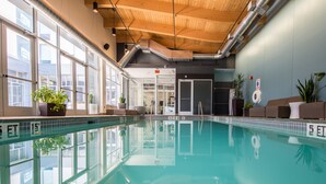 An indoor swimming pool with clear water, wooden ceiling, large windows, and potted plants. - Aloft by Marriott Nashville Franklin (Franklin)