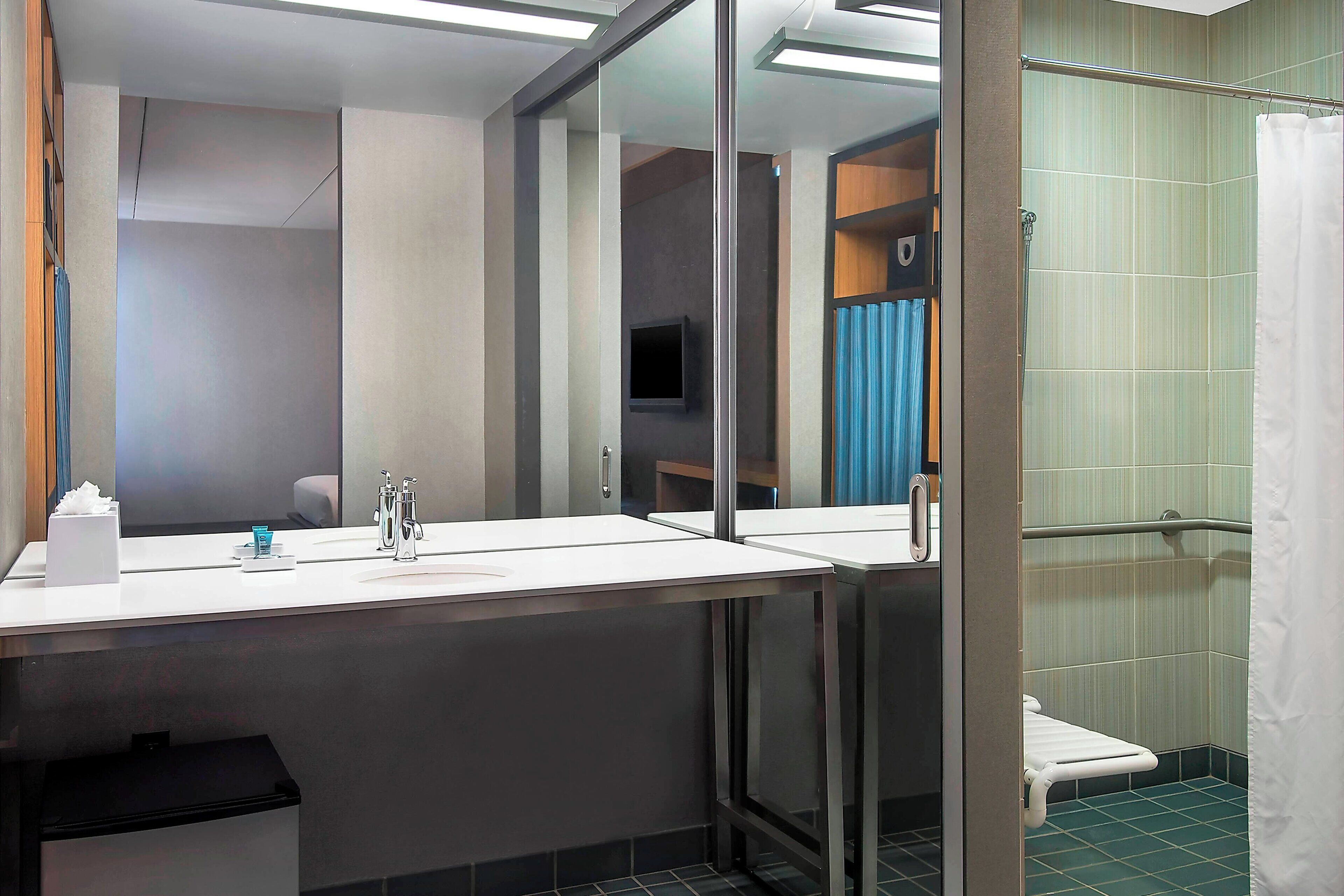 Un baño moderno con un espejo grande, un lavamanos y una zona de ducha.