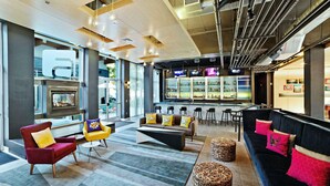 A modern lobby with seating areas, a bar, and a large window. - Aloft by Marriott Nashville Franklin (Franklin)