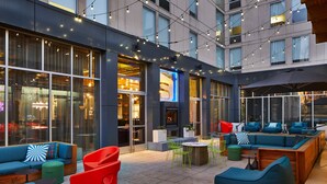 An outdoor seating area with sofas, chairs, and tables, featuring a modern design and large windows. - Aloft by Marriott Nashville Franklin (Franklin)