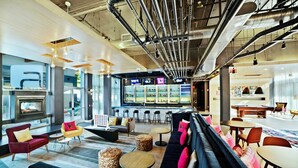 A modern lounge area with seating, a bar, and a fireplace. - Aloft by Marriott Nashville Franklin (Franklin)