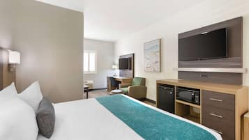 Una habitación de hotel con cama, escritorio, televisor y microondas.