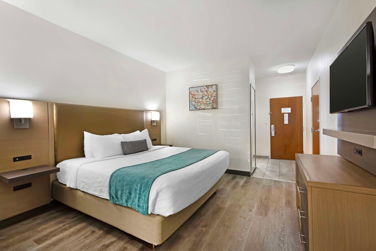 A hotel room with a bed, bedside tables, a TV, and a wooden cabinet.