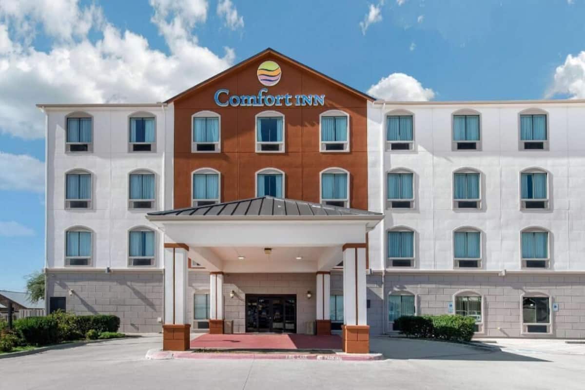A Comfort Inn hotel with a central entrance, multiple windows, and a clear sky.