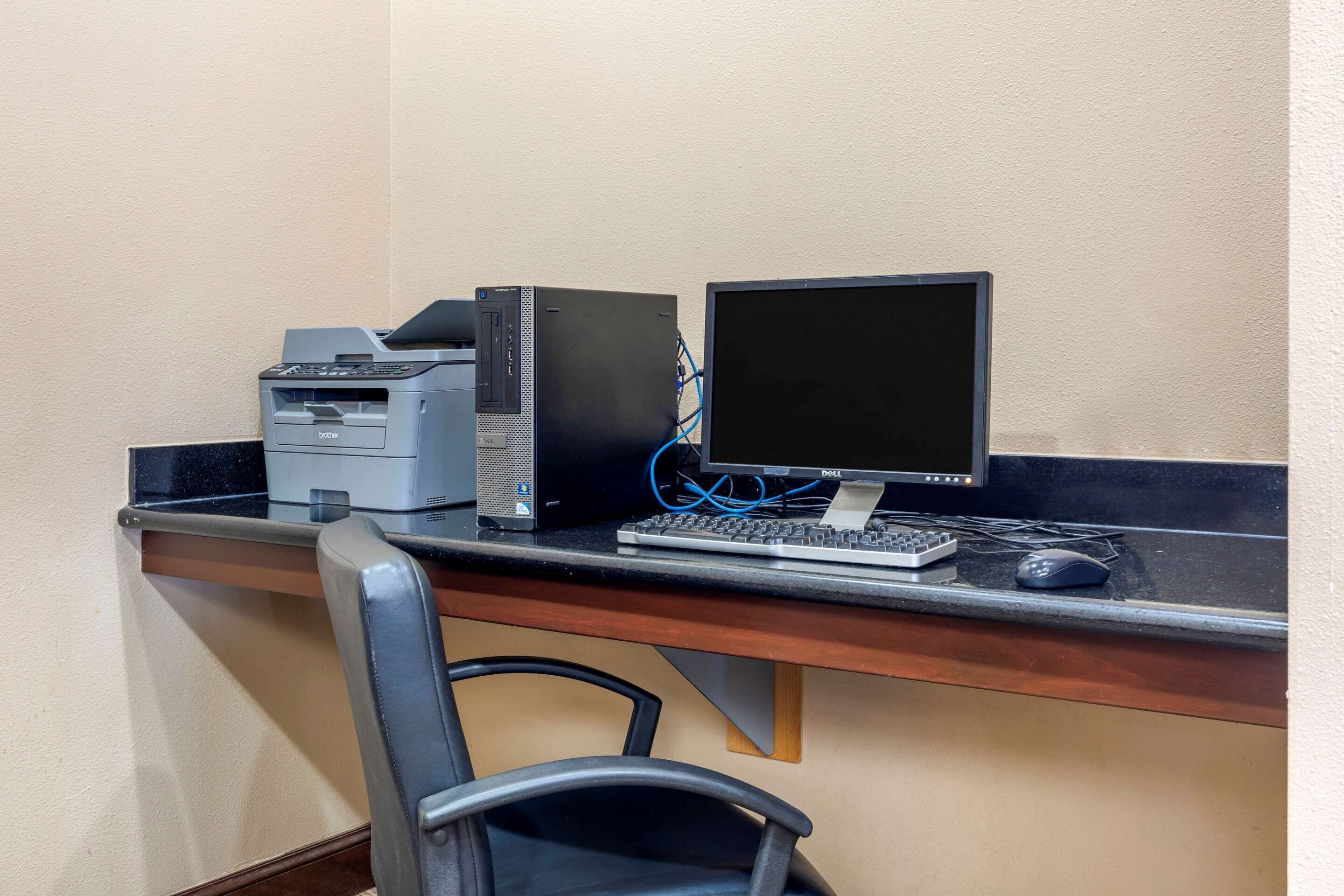 A desk with a desktop computer, monitor, keyboard, mouse, and printer.