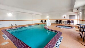 A swimming pool with a tiled edge, a hot tub, and a seating area with tables and chairs. - Comfort Inn Near UNT (Denton)