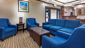 A hotel lobby with blue seating, a patterned carpet, and a framed picture on the wall. - Comfort Inn Near UNT (Denton)