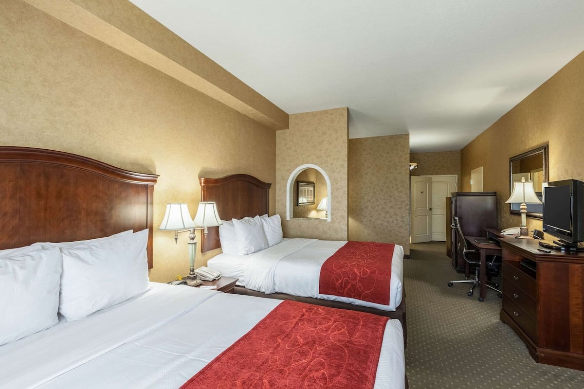 Een hotelkamer met twee bedden, een bureau, een televisie en een spiegel.