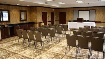 A conference room with a long table, chairs, a projector screen, and a presentation podium.