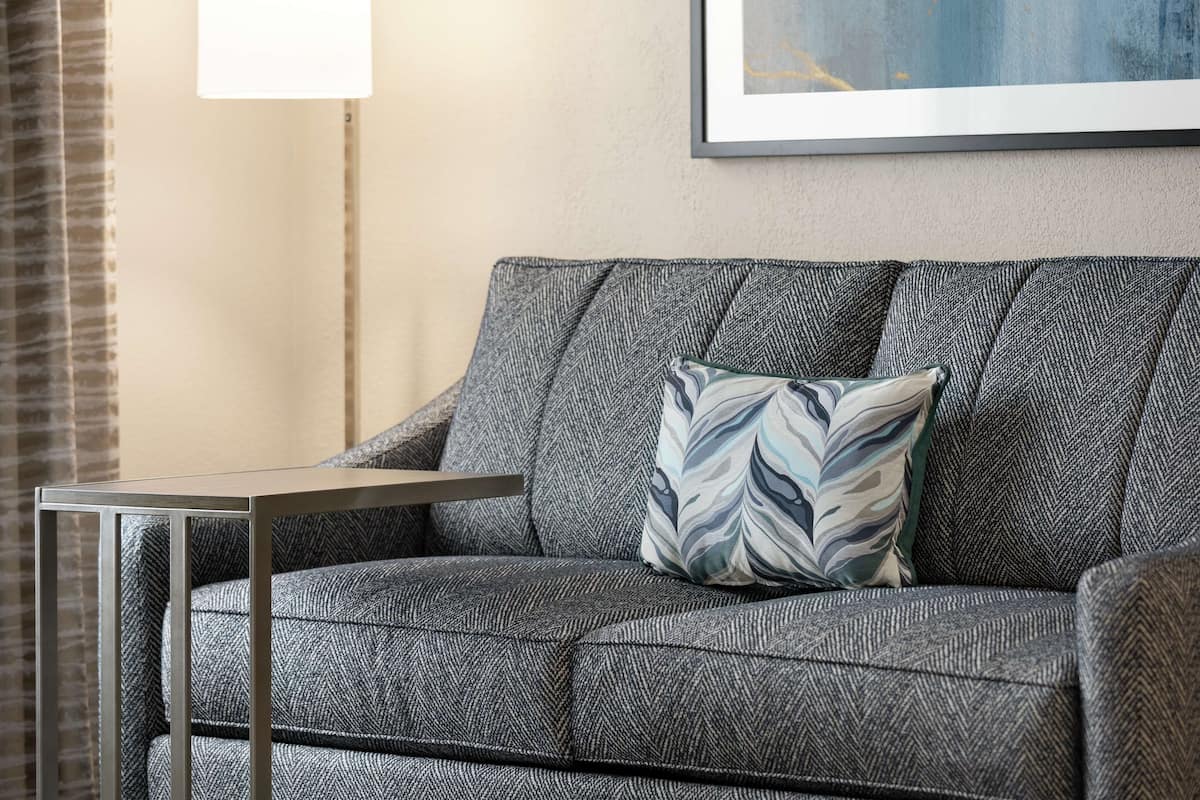 A grey sofa with a patterned cushion and a small table beside it.