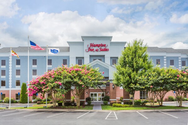 A Hampton Inn & Suites hotel with a brick facade, a large entrance, and a parking lot.