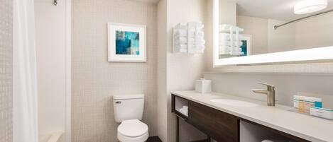 A modern bathroom with a white toilet, a large mirror, and a wooden vanity.