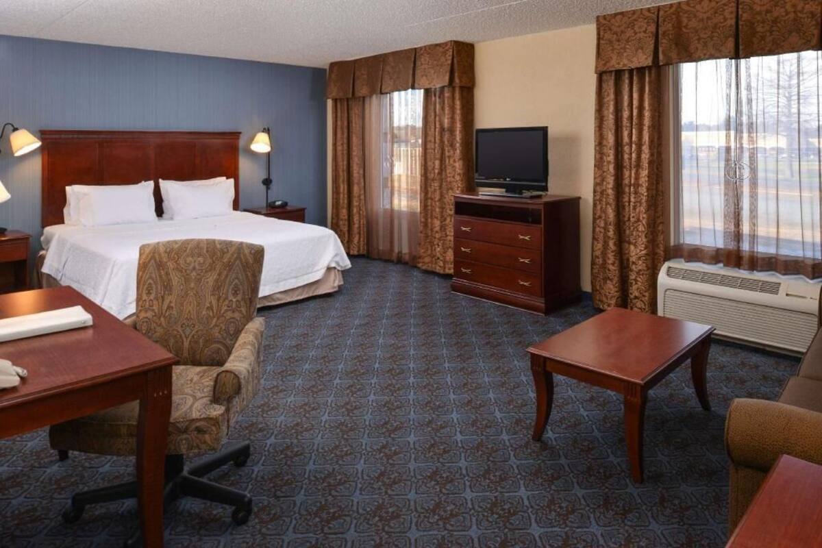 Une chambre d’hôtel équipée d’un lit, d’un bureau, d’une chaise, d’une télévision et d’une fenêtre avec des rideaux.
