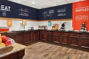 A kitchen area with wooden cabinets, a granite countertop, and a sign promoting waffles.