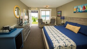 A bedroom with a bed, two chairs, a desk, and a view of the outdoors. - Strawberry Hill Seaside Inn (Rockport)