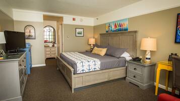 A bedroom with a bed, two bedside tables, a desk, a chair, and a TV.