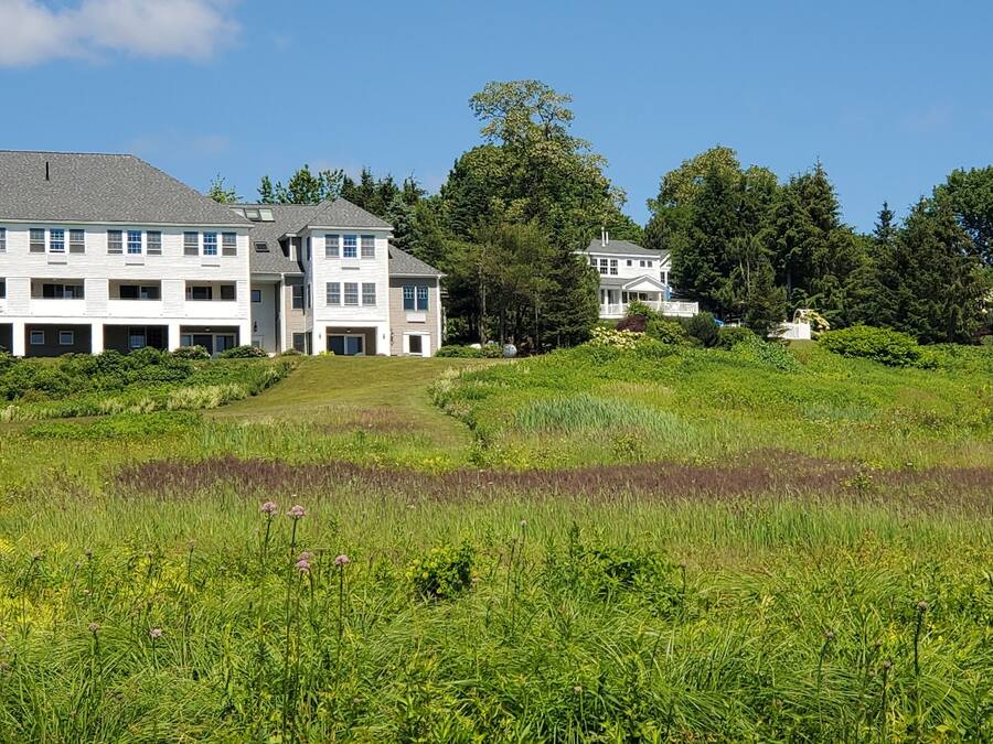 Un grand immeuble à étages, doté d’une façade symétrique, entouré d’une végétation luxuriante et d’une pelouse bien entretenue.