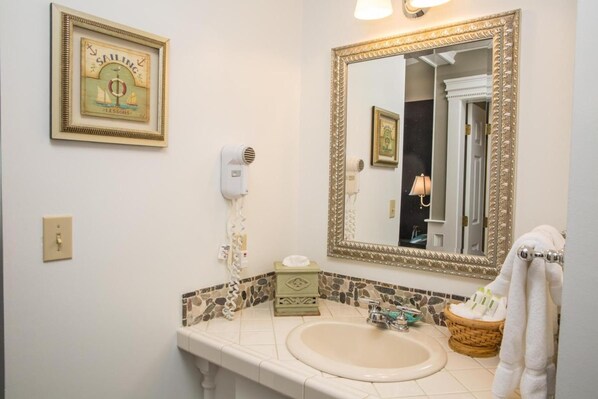 Un baño con un espejo grande, un lavabo, un secador de pelo y un perchero para toallas.