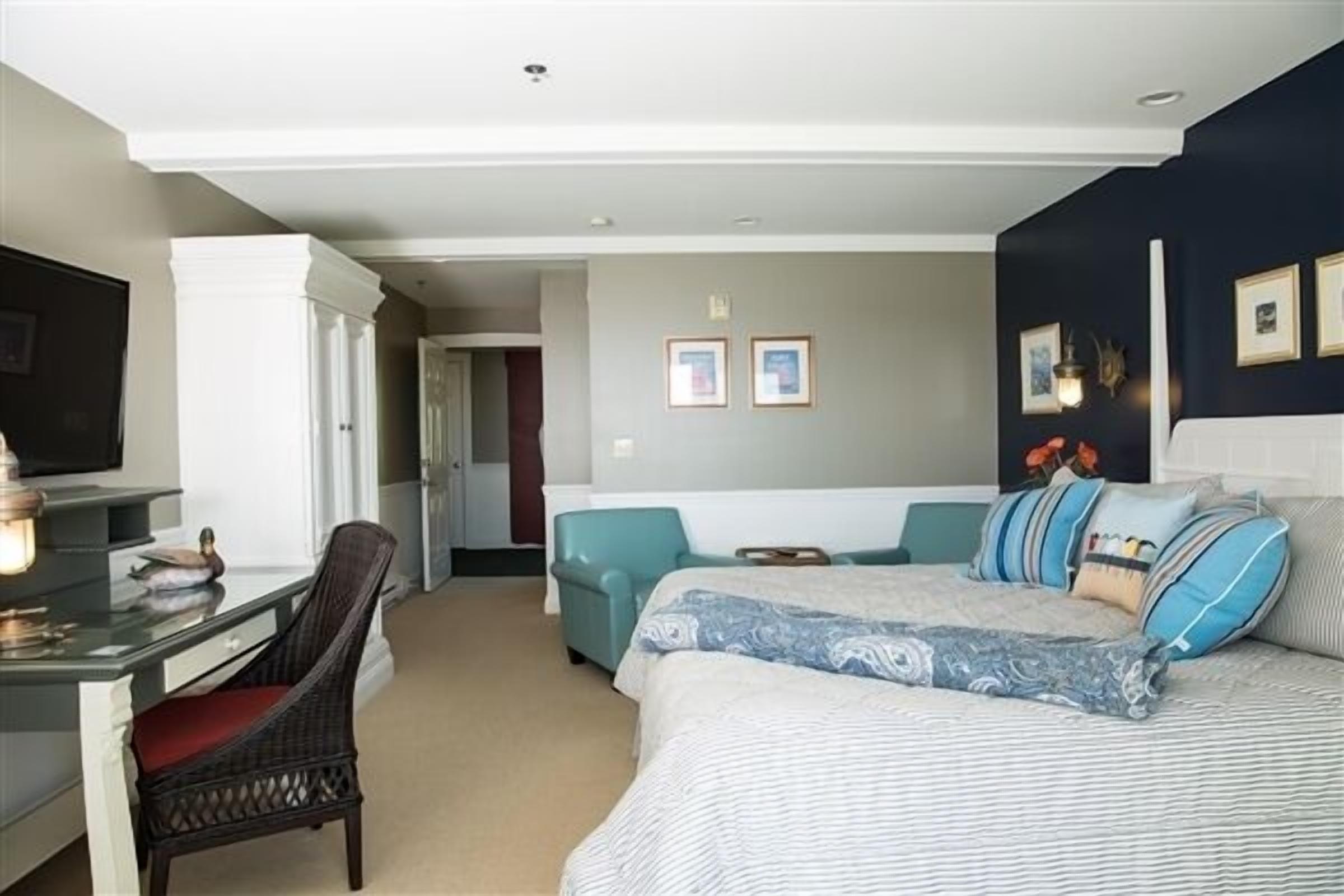A hotel room with a bed, a desk, a chair, and a sofa.