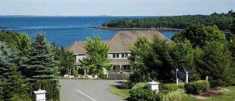 A residential area with a house, a driveway, and a view of the sea.