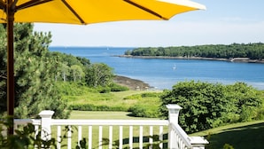 A coastal view with a grassy area, a white fence, and a yellow umbrella.