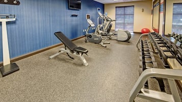 Ein Fitnessstudio mit Trainingsgeräten, einer Gewichtbank und einer Waage.