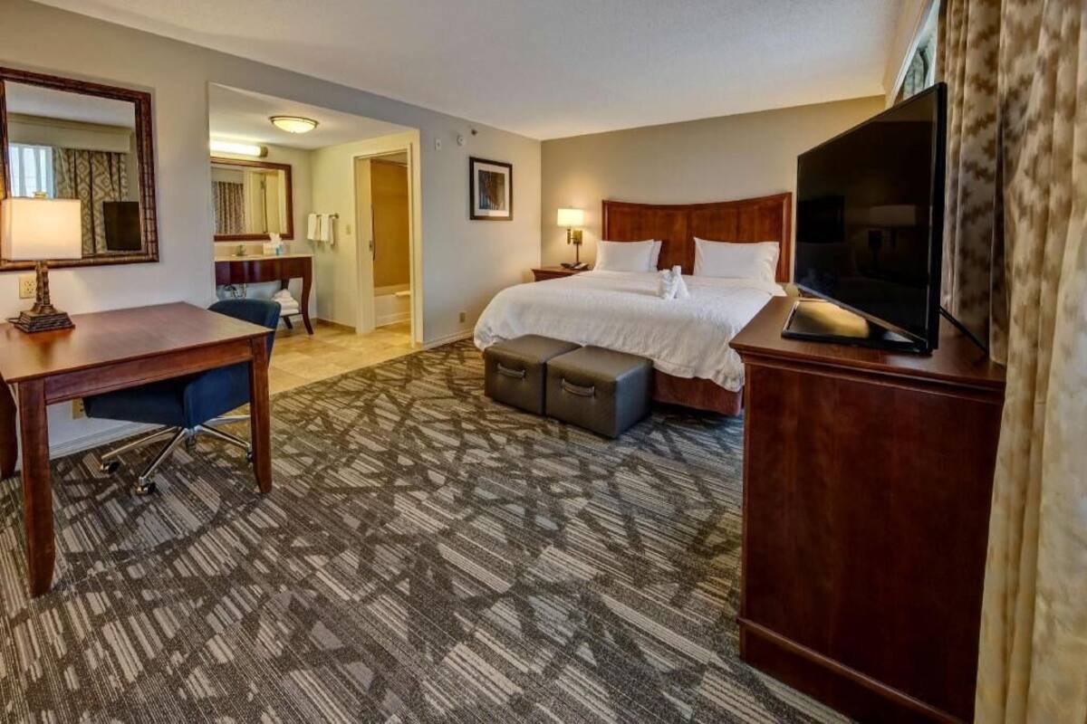 A hotel room with a bed, a desk, a television, and a bathroom.