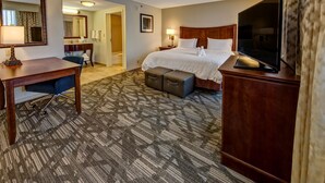 A hotel room with a bed, a desk, a chair, a television, and a bathroom visible through an open door. - Hampton Inn & Suites Stuart-North (Stuart)