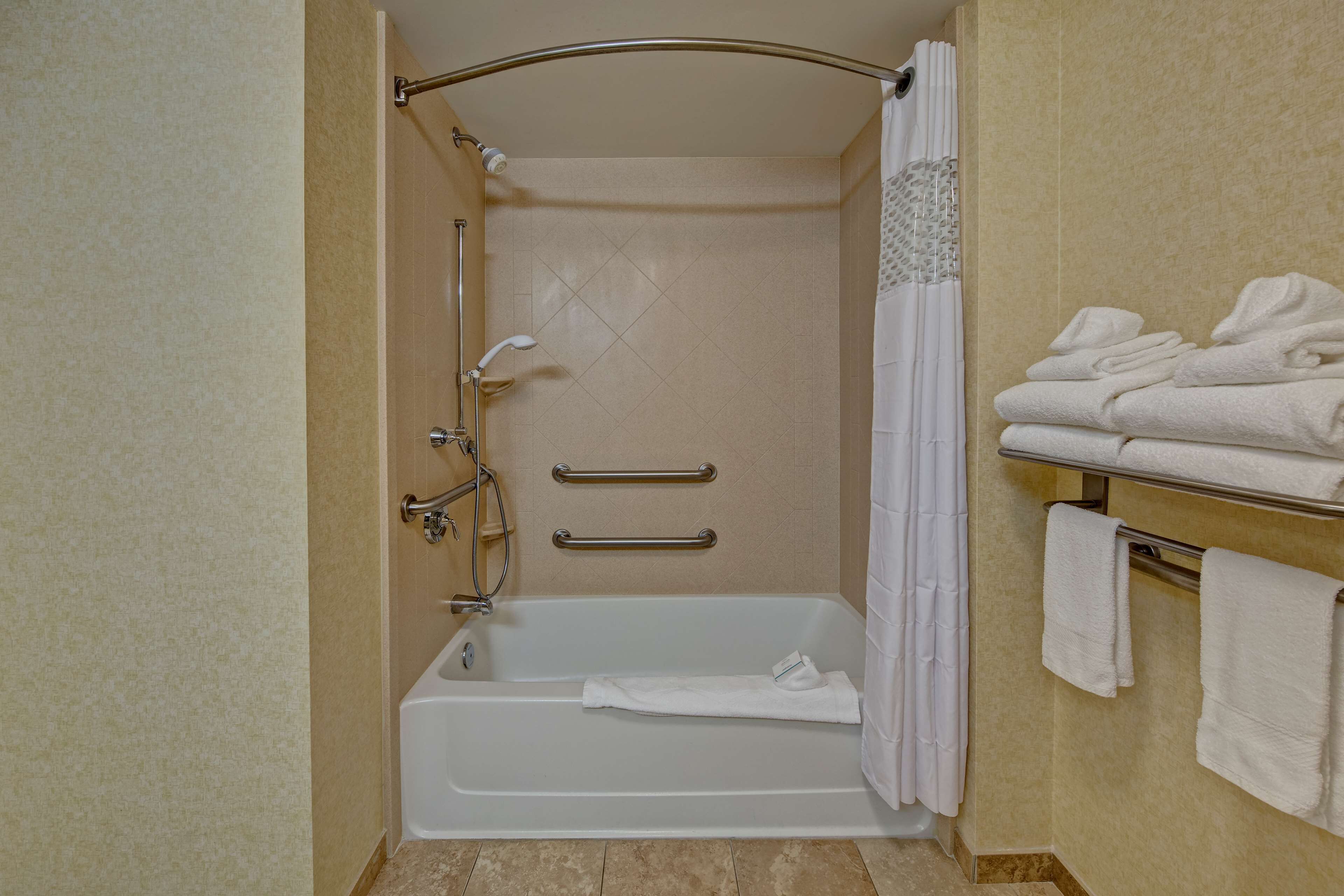 A bathroom with a bathtub, shower, and towel rack.