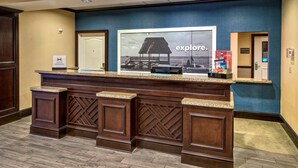 A reception desk with a large poster of a beach scene and the word "explore." - Hampton Inn & Suites Stuart-North (Stuart)